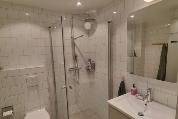 Modernt badrum i Stockholm med duschvägg i glas och klinkergolv